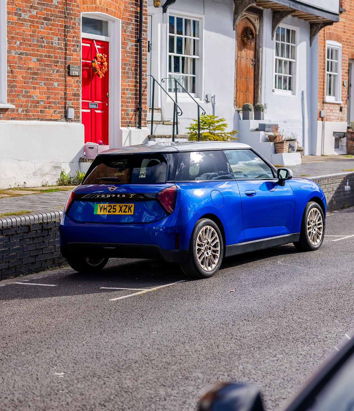 Rear view of the MINI Cooper in Sunnyside Yellow with Black Roof parking.